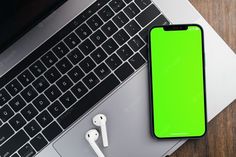 an iphone and ear buds sitting on top of a laptop computer next to a keyboard