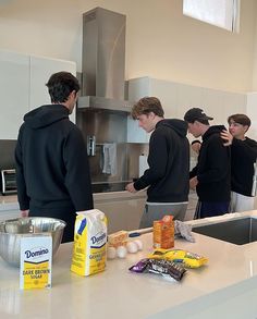 several people in a kitchen preparing food on a counter top with milk, eggs and other ingredients