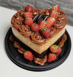 two heart shaped cakes with chocolate frosting and strawberries on top are sitting on a black plate