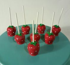 chocolate covered strawberries with toothpicks in the shape of tomatoes on a blue plate