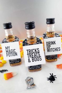 three bottles of booze sitting on top of a table next to halloween candies