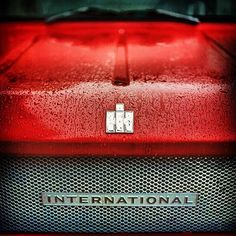 the front end of a red truck with rain drops on it's grills