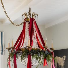 a chandelier with red and white ribbons hanging from it's centerpiece