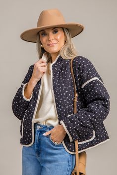 This quilted jacket is covered in a ditsy floral print, and a natural piping contrast trims the edges. The relaxed fit features hook closures down the front, a standing collar, and dropped shoulders. Patch pockets on the front complete the look. Casual Outerwear With Floral Print For Daywear, Trendy Quilted Jacket With Padded Collar For Spring, Trendy Spring Quilted Jacket With Padded Collar, Spring Trendy Quilted Jacket With Padded Collar, Casual Spring Outerwear With Padded Collar, Casual Quilted Jacket For Spring Workwear, Casual Quilted Jacket With Padded Collar For Spring, Trendy Outerwear With Contrast Stitching, Fall Floral Print Outerwear With Stand Collar