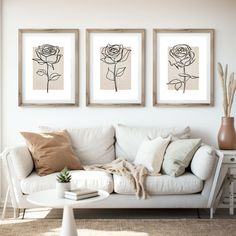 three black and white roses are hanging on the wall above a couch in a living room