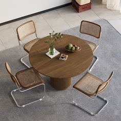 a round wooden table with four chairs and a bowl of fruit on the dining room table