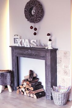 a fireplace with logs stacked in front of it and a clock on the wall above