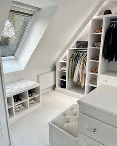 an attic bedroom with white closets and shelves filled with clothes, shoes and other items