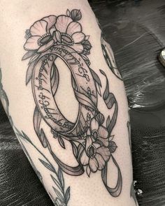 a tattoo on the leg of a woman with flowers and an oval frame in it