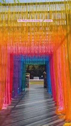 an archway decorated with multicolored streamers and hanging from it's sides