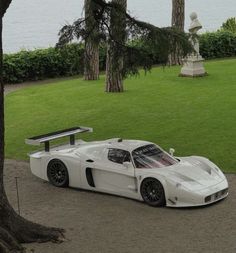 a white sports car parked on the side of a road in front of some trees