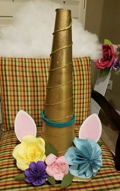 some paper flowers sitting on top of a chair next to a fake unicorn head and horn