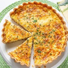 a quiche on a green and white plate with one slice missing from the pie