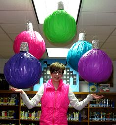 a woman is standing in front of some paper balls and holding them with both hands