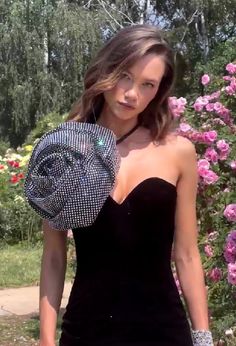 a woman in a black dress holding a hat