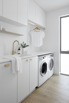 a washer and dryer in a white laundry room next to a large window