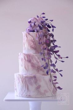 a three tiered cake with purple flowers on top