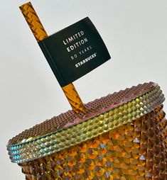 an orange and gold vase with a black flag sticking out of it's top