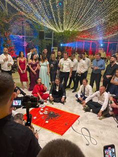 a group of people standing and sitting around each other in front of a red carpet