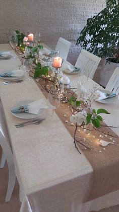 the table is set with white flowers and place settings for two people to sit at