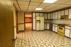 an empty kitchen with white cabinets and yellow appliances