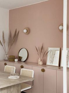 a dining room with pink walls and white chairs