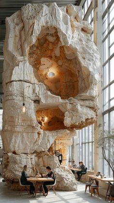 two people sitting at tables in front of a large rock structure that looks like it has been built into the side of a building