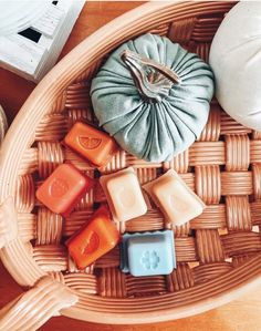 some soaps are sitting on a wicker tray with other items in it and an orange pumpkin is next to them