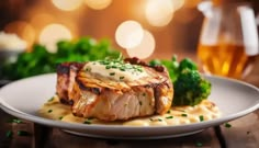 a white plate topped with meat and broccoli next to a glass of beer