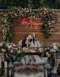 a couple sitting at a table in front of a sign that says the agogoss