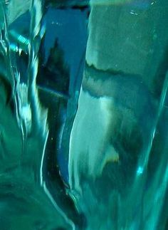 an abstract photograph of water flowing down the side of a glass vase with blue and green colors