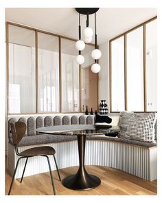 a dining room table with chairs and lights hanging from it's ceiling over the couches