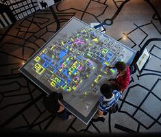 three children looking at a large map on display