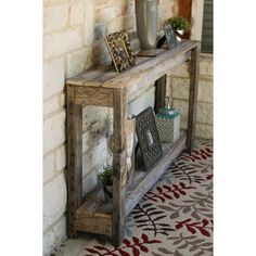 a wooden shelf sitting on top of a rug next to a brick wall with pictures and plants