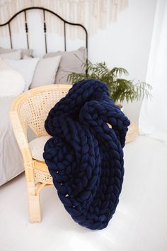 a large blue blanket sitting on top of a bed next to a wicker chair