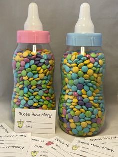 two baby bottles filled with lots of candy next to some cards for guess how many?