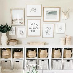 a dining room table with some baskets on top of it and pictures above the table