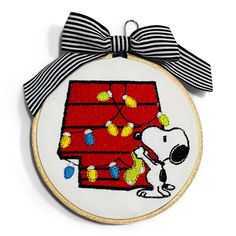 a snoopy christmas ornament with a black and white striped bow on it