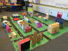 a group of children's play area with cardboard buildings and toys on the floor