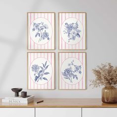 three blue and white flowers are hanging on the wall next to a vase with dried flowers