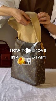 a person holding a brown louis vuitton bag with the words how to remove ink stain