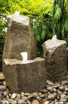 two large rocks sitting next to each other on top of a pile of stones and gravel