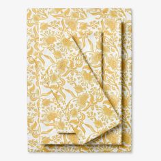 a yellow and white floral print napkin on top of a folded piece of paper with an orange flower pattern