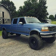 a blue pick up truck parked in front of a barn