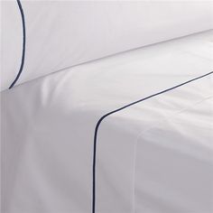 a bed with white sheets and blue trim