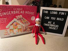 an elf is sitting next to a gingerbread house book and a sign that says, this looks fun can you build a gingerbread house?