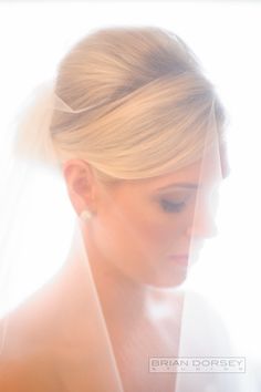 a woman in a wedding dress looking down at her cell phone while wearing a veil