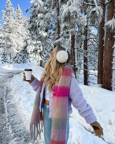 a woman walking in the snow holding a cup of coffee