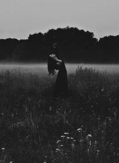 black and white photograph of two people standing in the middle of a foggy field