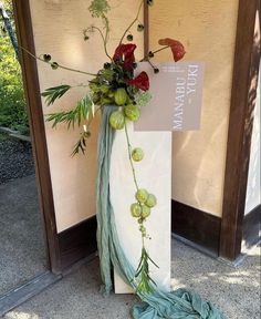 a tall vase with flowers and vines on it sitting in front of a sign for the library